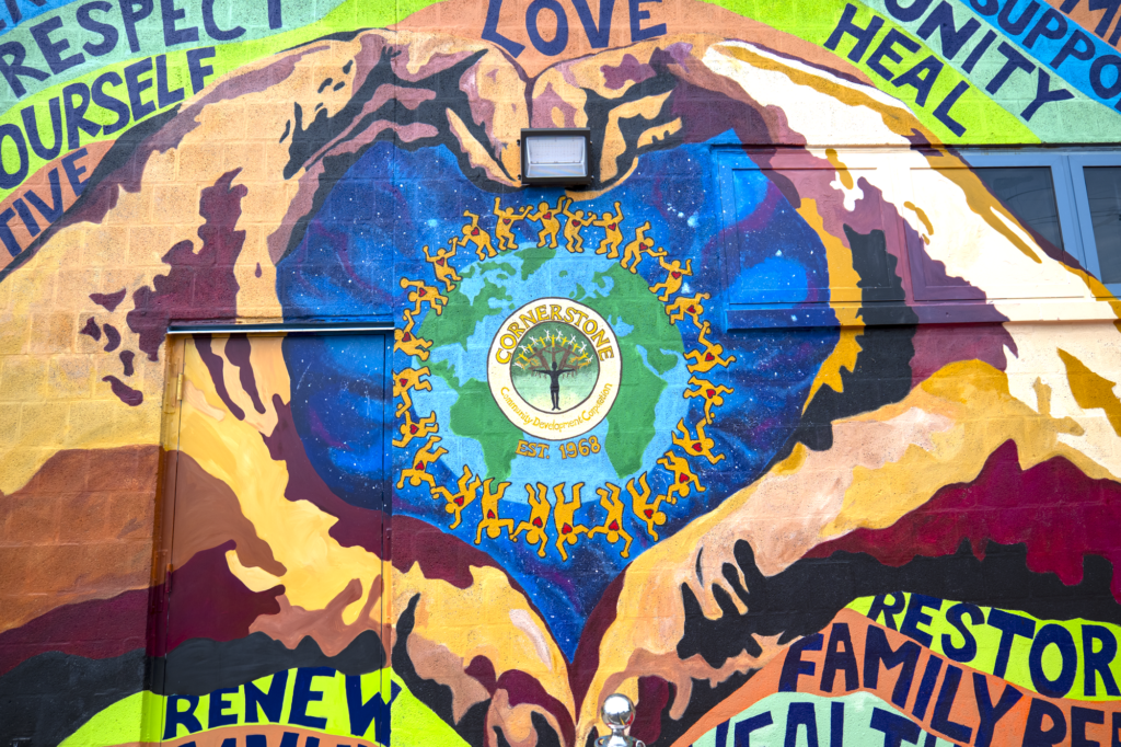 Un primer plano del mural del Centro de Desarrollo Comunitario Cornerstone, en Ford Heights, en el que se ven unas manos formando un corazón alrededor del logotipo del centro.