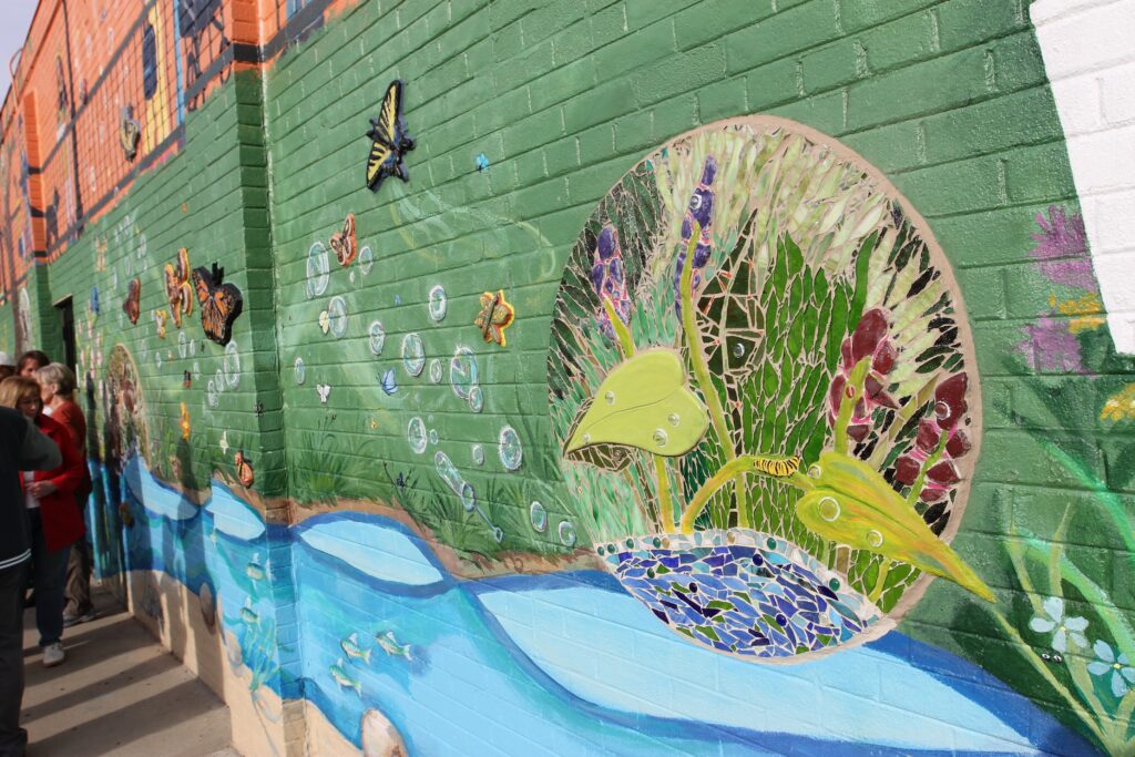 A close-up of the new downtown Glenview mural showing a colorful mosaic of wildlife and plants in a green stripe.