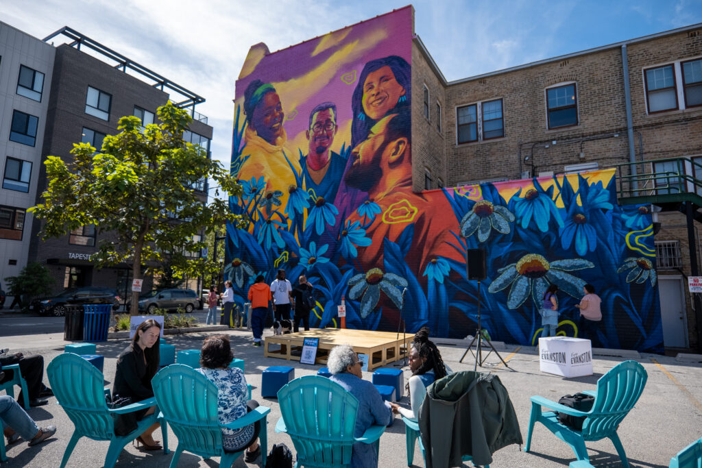 A colorful purple, pink, yellow, red, and blue mural adorns the side of the Open Studio Project building in Evanston.