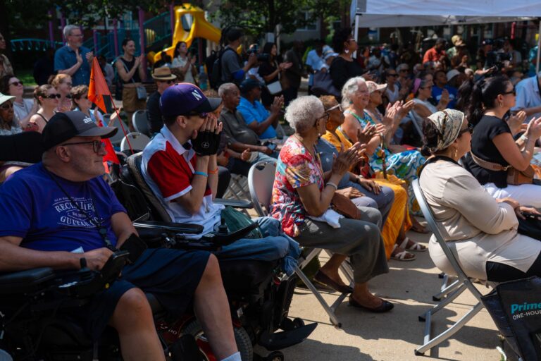 Los asistentes al acto de inauguración del proyecto «ARTSiE Creative Placemaking» se sientan y aplauden durante los discursos del evento.